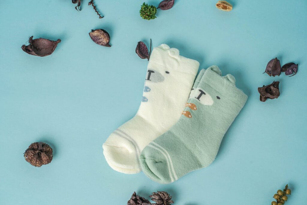pexels-photo-14195487 Adorable baby socks on a pastel blue background with decorative elements, perfect for baby fashion themes.