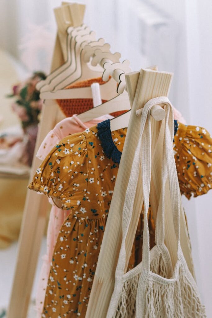 pexels-photo-15625985 Wooden hangers displaying colorful children's dresses in a boutique setting.